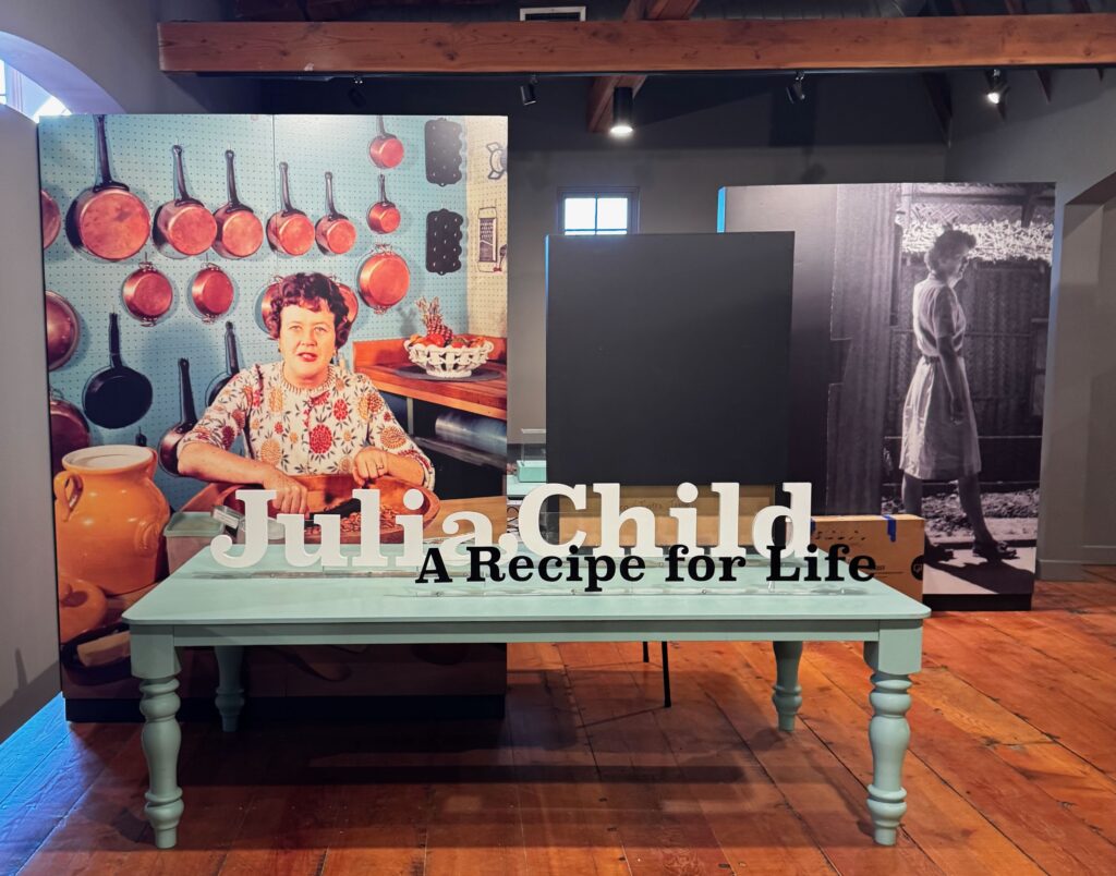 Photo of chef Julia Child at a table with copper pots and pans.